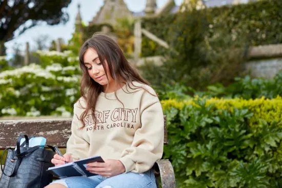 Female Student in front of Abbey working in a notebook