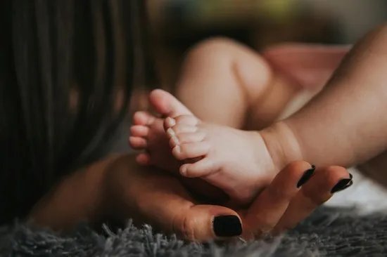 A woman's hands holding a baby's feet