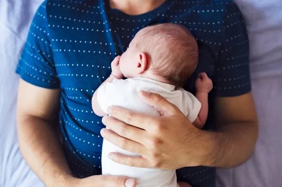 A man holding a sleeping baby