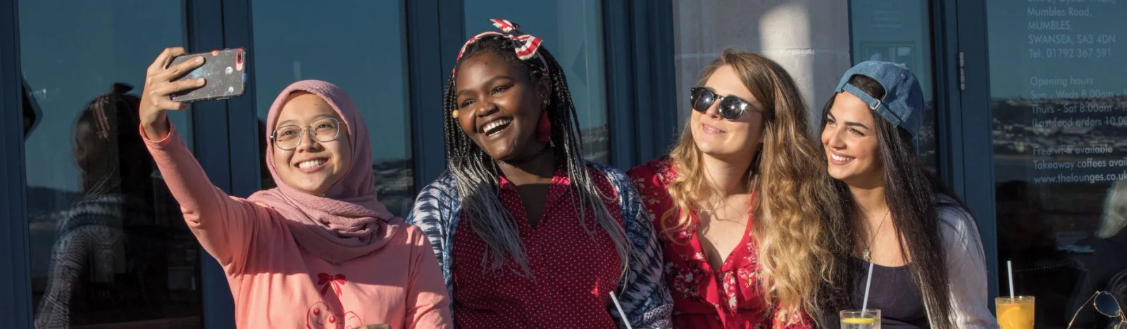 Students taking a photo of themselves sitting outside enjoying a drink